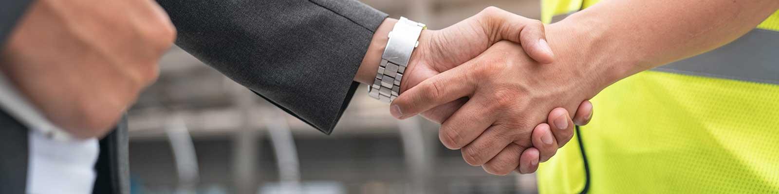 close up of handshake between man in suit and construction vest