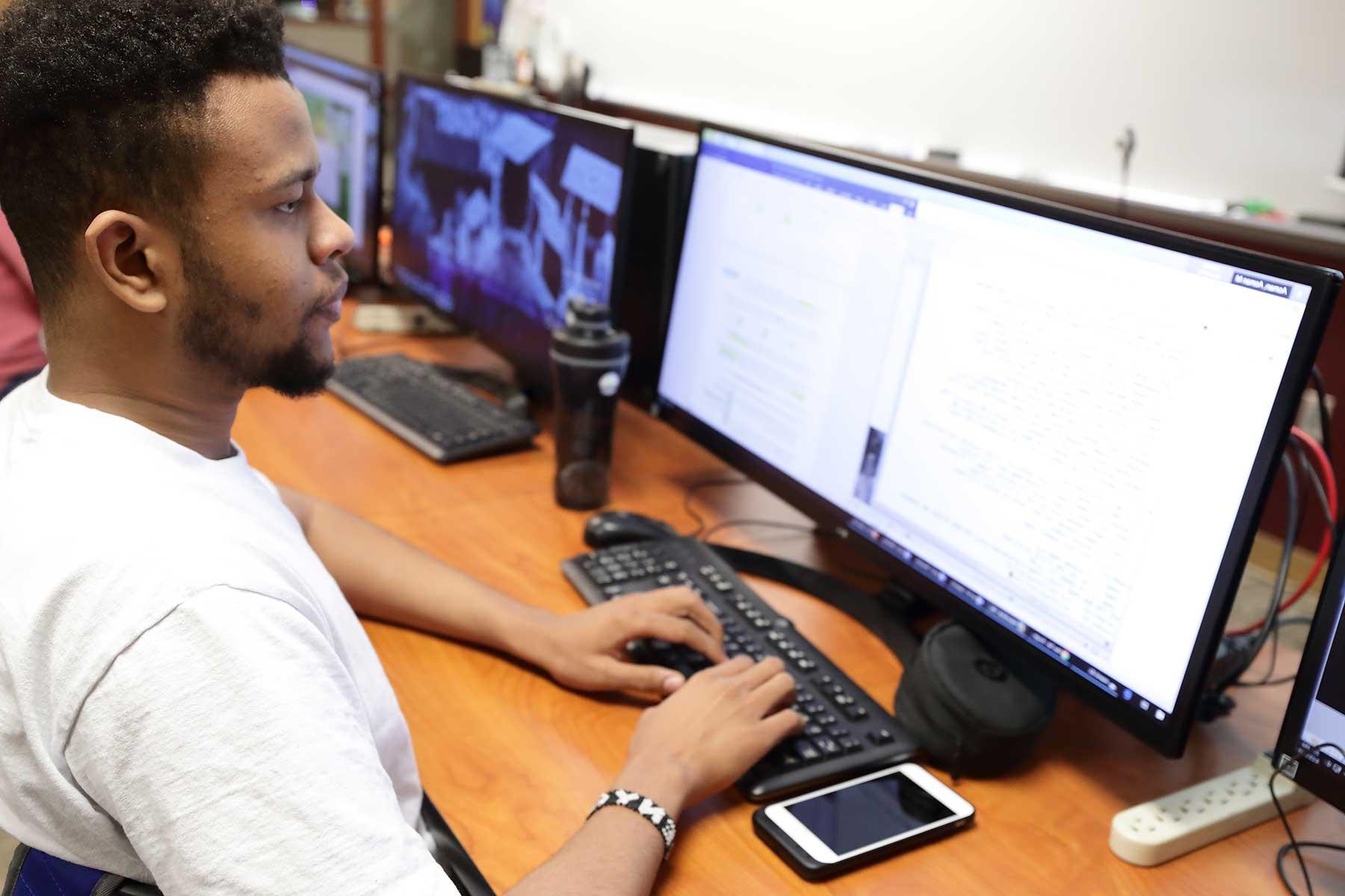 student in front of dual computer monitors